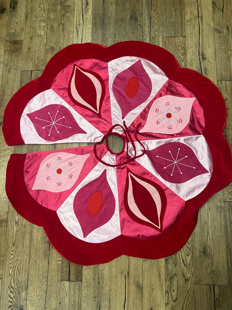 1 round large pink ornament tree skirt pink with various ornaments with a ribbon to tie skirt